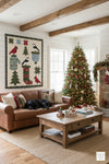 Cozy living room with a Christmas tree, Christmas Lap Quilt by Coach House Designs, and a brown sofa.