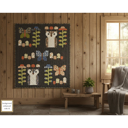 Lap quilt with butterfly blocks, owl blocks, flower blocks and mushroom blocks hanging on a wooden wall in a room with a window and chair.