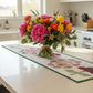 Quilted Gigi's Table runner on kitchen counter with bouquet of flowers on top. Ai generated.